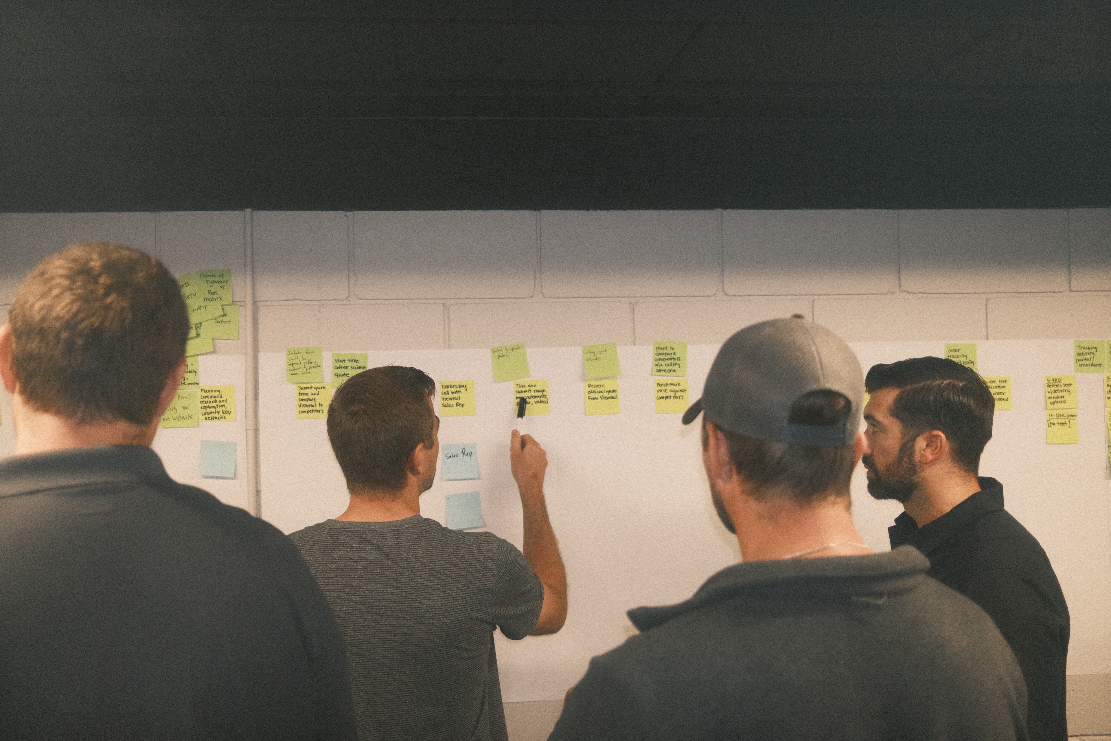 Team collaborating at a whiteboard covered with sticky notes during a service blueprint workshop